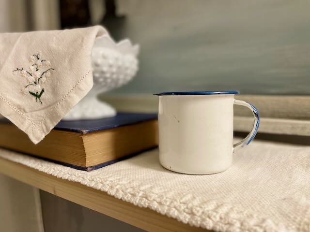 a blue and white enamel cup styled on a bathroom shelf