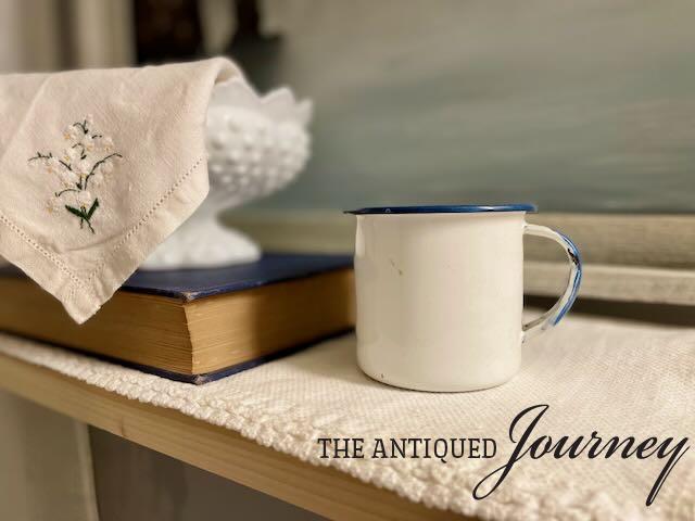 a blue and white enamel cup styled on a bathroom shelf