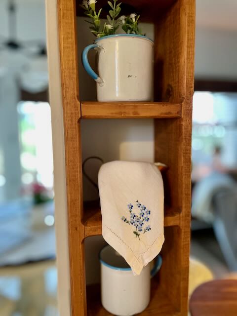 blue and white enamel cups displayed in a kitchen cubby shelf