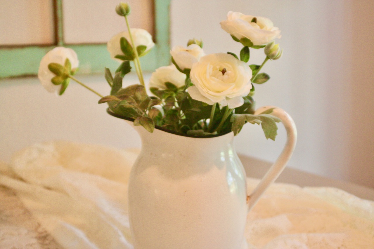 white enamelware pitcher displayed with white flowers