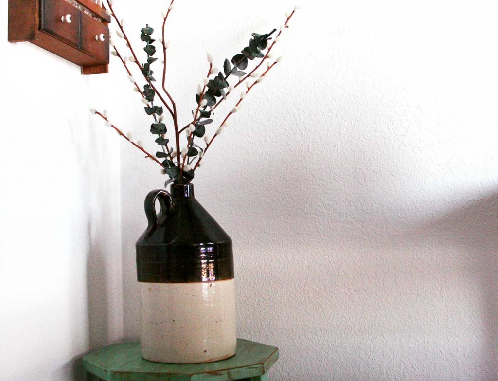 a vintage crock filled with faux greenery