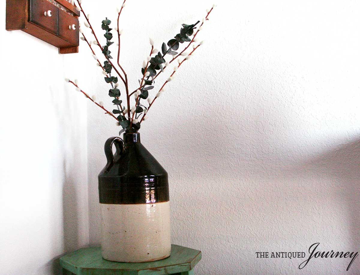 a vintage crock filled with faux greenery