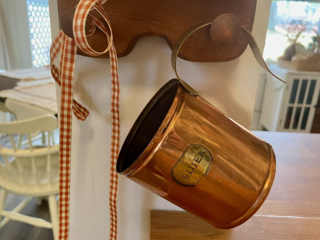 a vintage copper pint container hanging on a peg rack