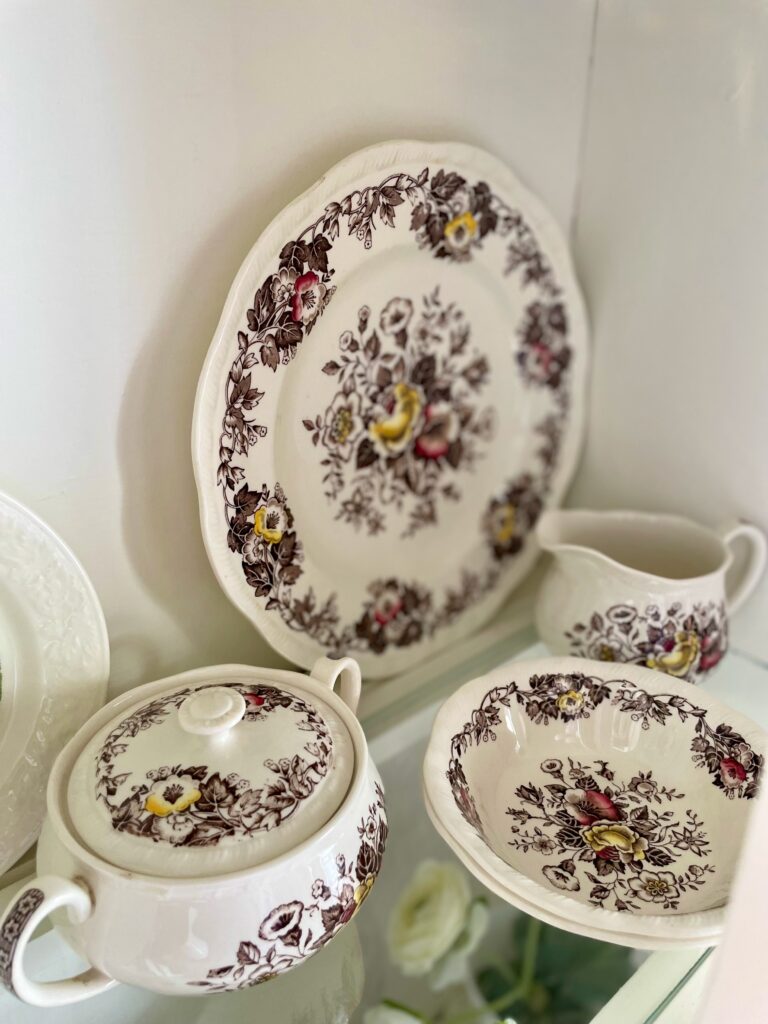 a set of vintage transferware dishes displayed in a hutch