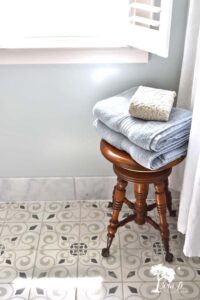 an antique piano stool used to hold towels in a bathroom