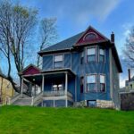 a blue and purple Queen Anne style Victorian house on a hill