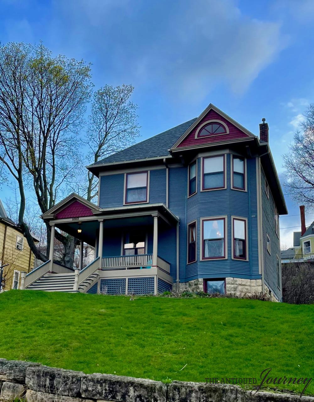 a blue and purple Queen Anne style Victorian house on a hill