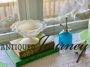 a scalloped milk glass pedestal bowl displayed on top of vintage books
