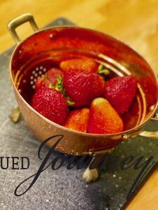 a vintage copper strainer filled with fresh strawberries