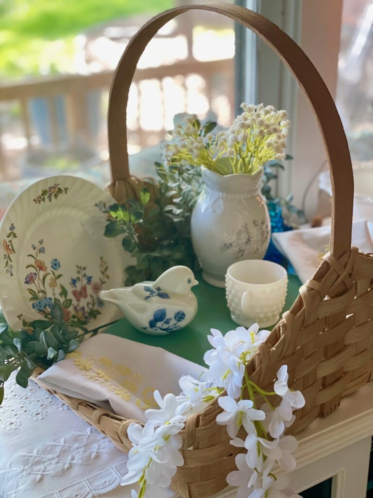 a vintage basket filled with floral dishes and decor for summer