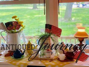 a vintage patriotic display with enamelware, milk glass, wooden elements and faux yellow florals
