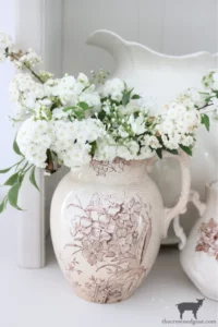 an antique brown and white transferware pitcher filled with fresh flowers