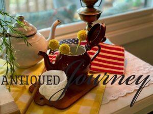a vintage patriotic vignette with enamelware, milk glass, and books