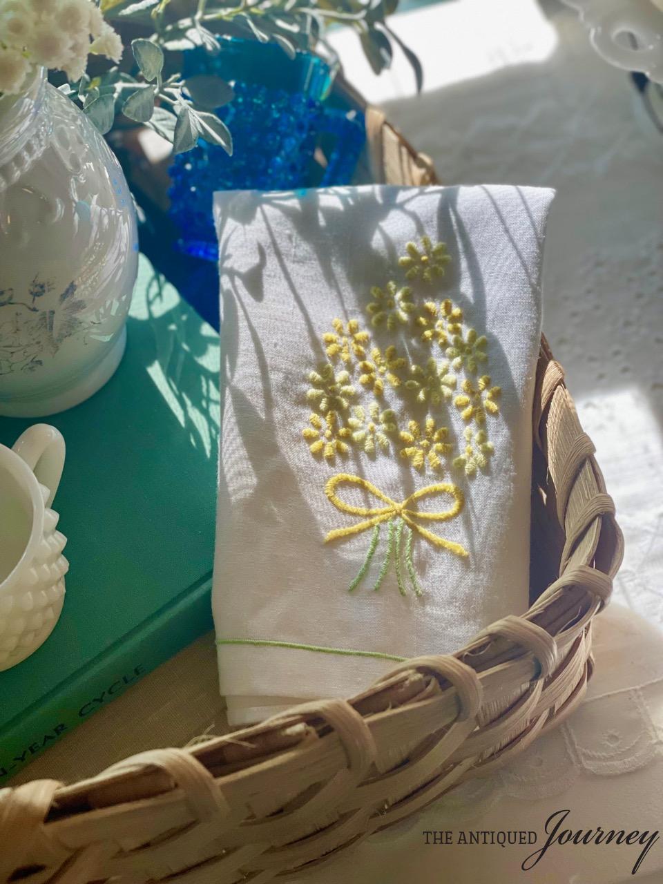 a vintage linen napkin with yellow flowers in a summer vignette
