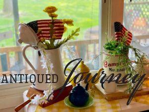 vintage enamelware and a vintage tin displayed with faux stems for a patriotic vignette