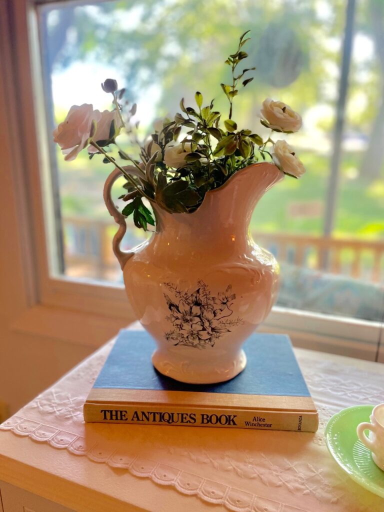 an antique transferware pitcher displayed on top of a vintage book