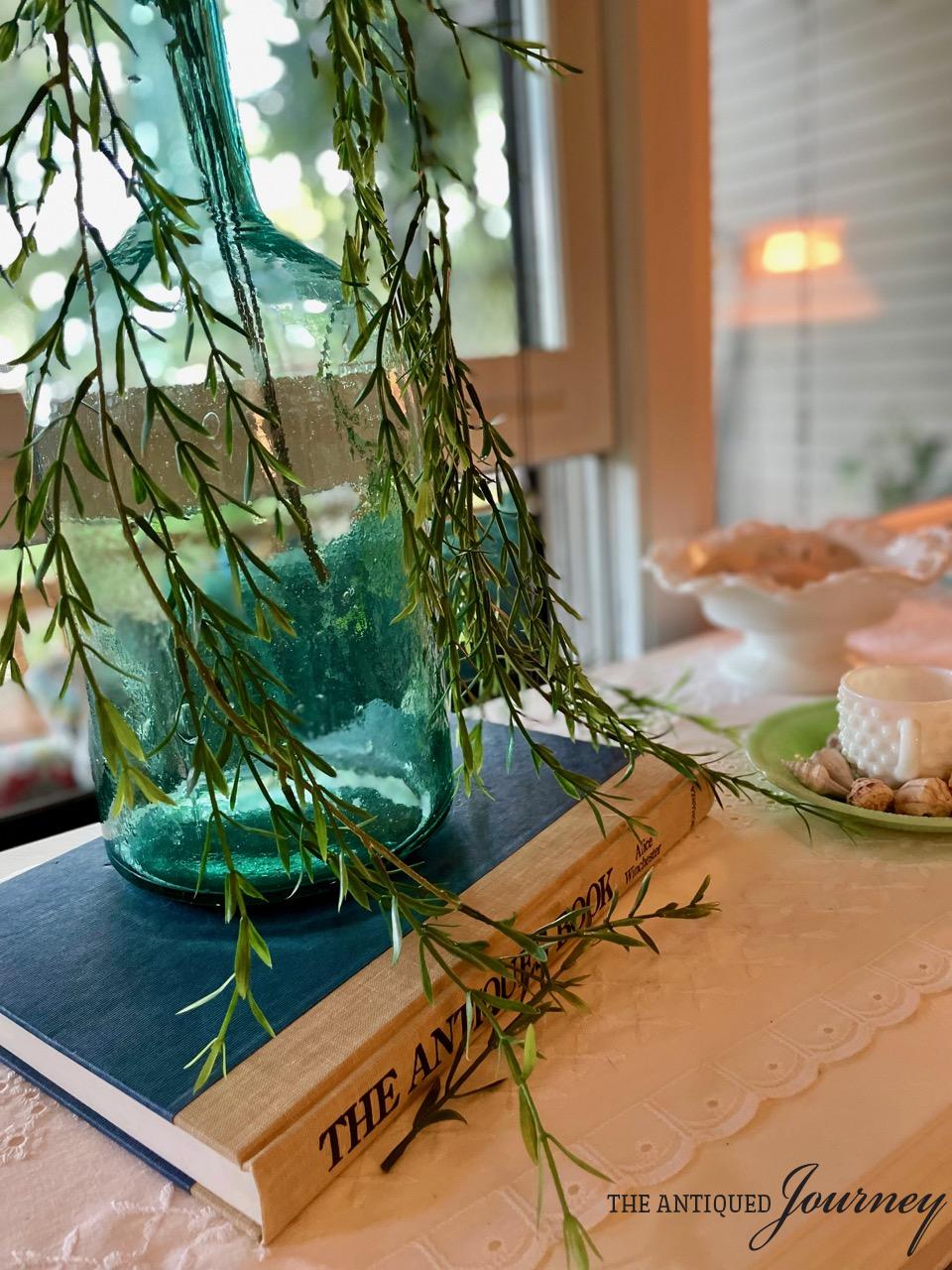 a vintage blue jug filled with faux greens in a coastal display