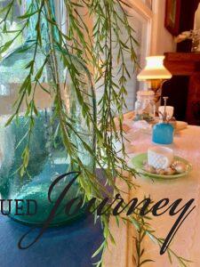 a teal blue jug with faux greenery