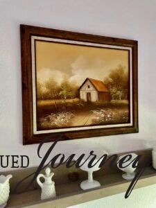 a vintage oil painting of an old barn displayed with vintage milk glass