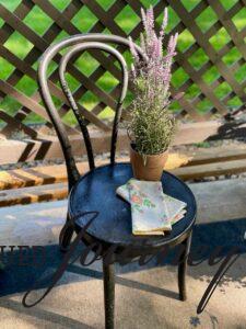 an outdoor black bistro chair styled with a lavender plant and linens