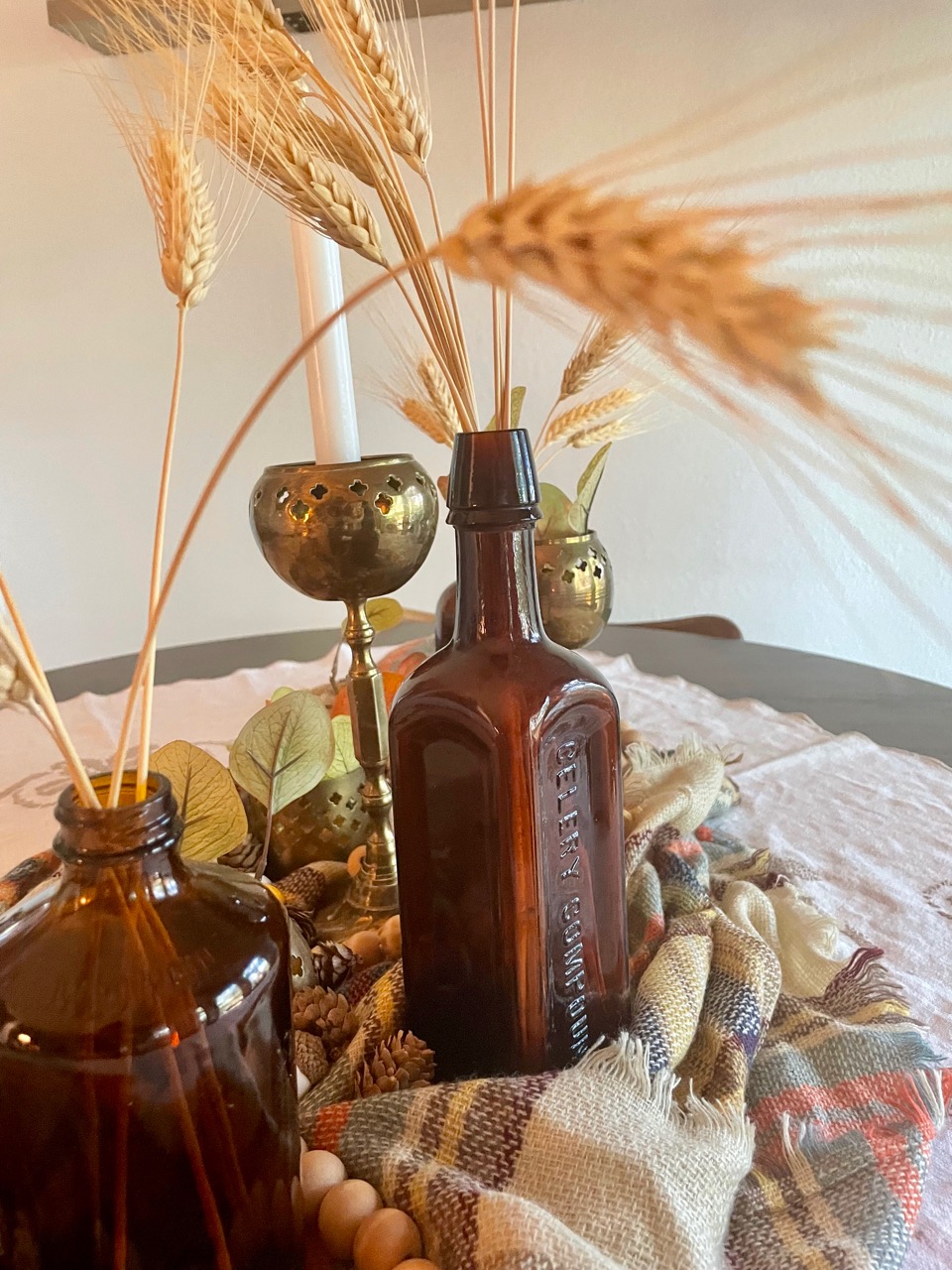 a fall centerpiece with vintage amber bottles and wheat grass