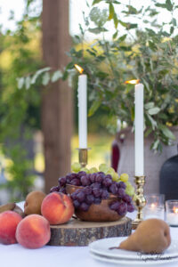 a fall table center piece with brass candlesticks and fruit