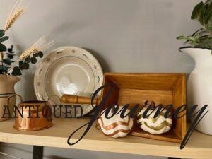 a bathroom shelf decorated for fall with copper and pumpkins