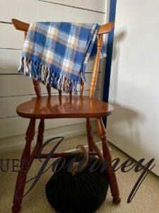 a vintage wooden chair displayed with a plaid blanket and a thrifted faux pumpkin