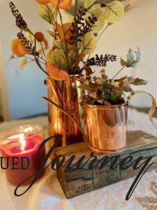 a fall centerpiece with vintage copper and a candle