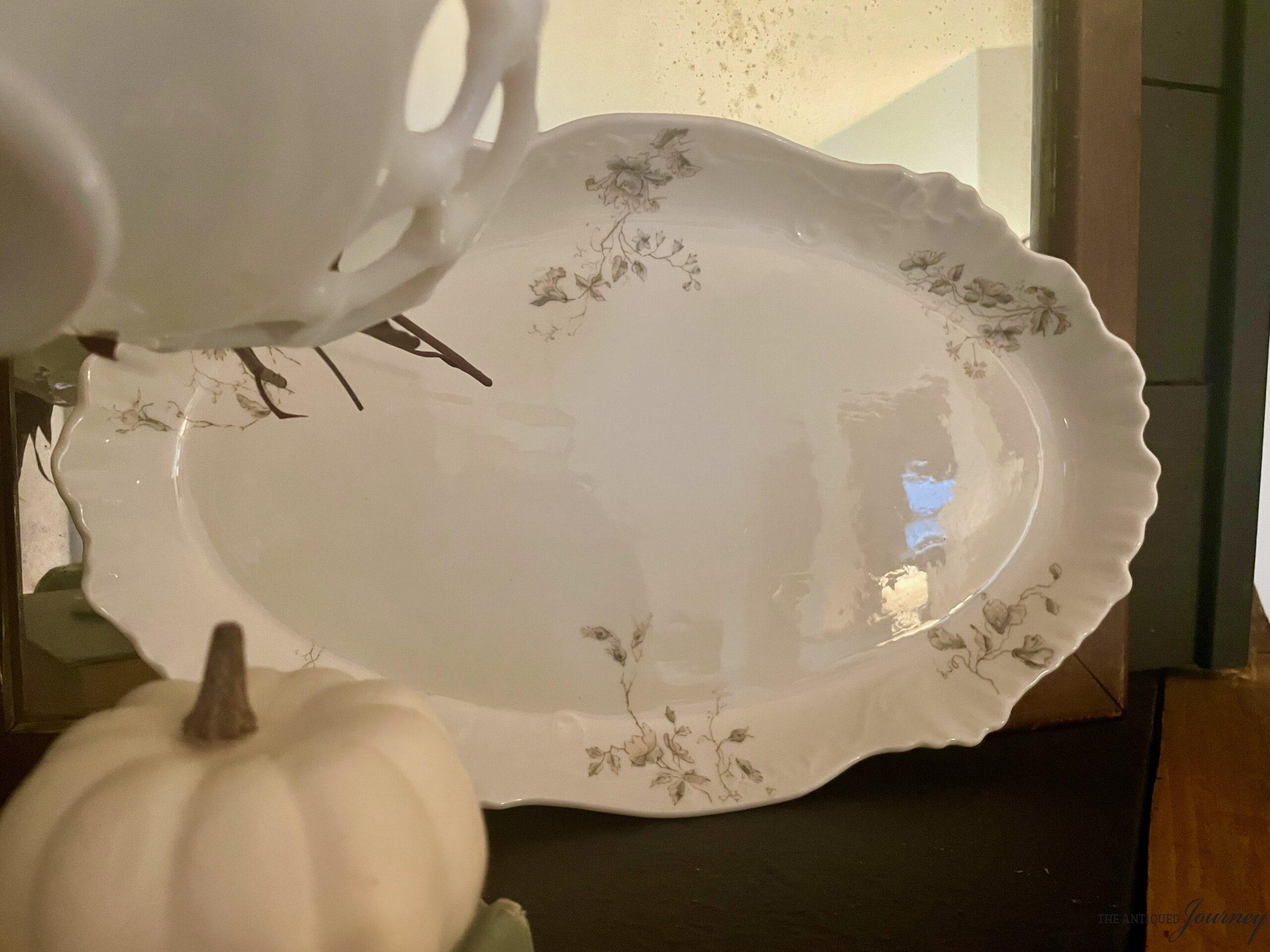 a vintage Ironstone platter on a mantel with an antique mirror