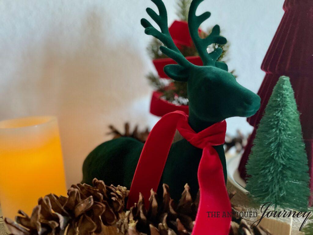 a velvet reindeer amongst bottle brush trees and pinecones