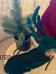 a Christmas vignette with trees and a green velvet reindeer