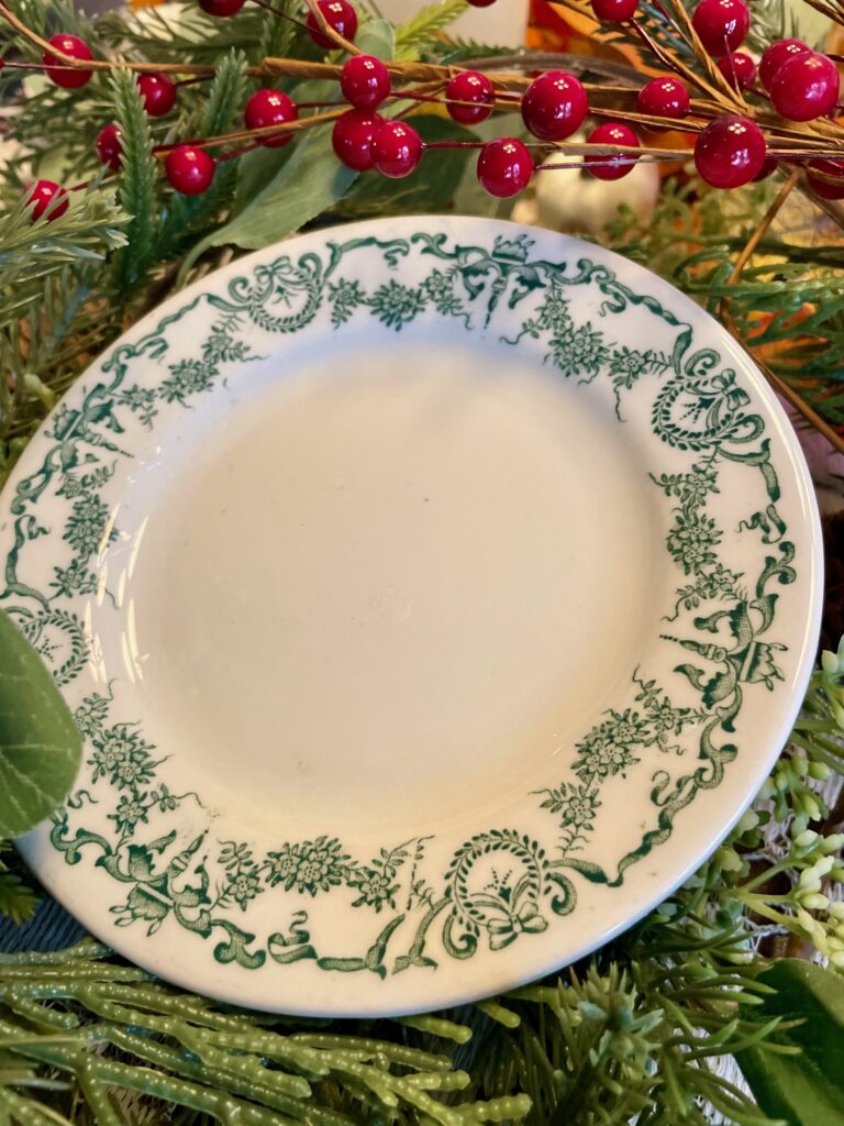 a vintage Christmas plate surrounded by berries and greenery