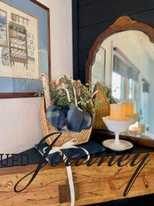 a winter mantel with a basket, candle, book, and milk glass