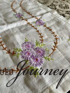 a vintage table runner with embroidered purple flowers