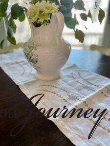 a vintage linen with purple flowers and an antique vase