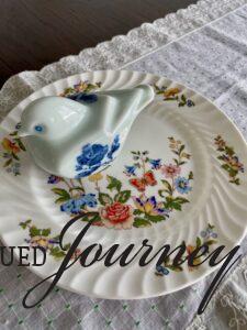 a vintage ceramic bird on a vintage floral plate for a cloche display