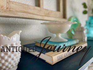 milk glass styled on a shelf for Spring with vintage books