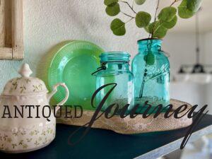 vintage blue jars styled with faux eucalyptus on a shelf 