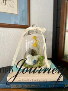 a DIY Spring cloche with moss and a bird's nest displayed on a mantel