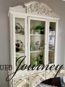 a white hutch styled with vintage decor
