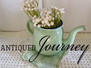 a mint green enamel teapot with faux stems used in a white hutch for Spring