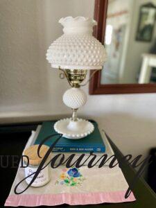 a vintage milk glass lamp on a credenza 