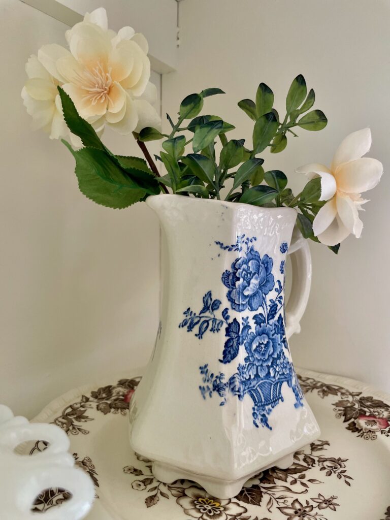 a vintage blue and white transferware vase displayed in a hutch