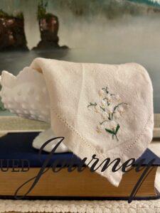 an embroidered hanky with white flowers on a vintage book