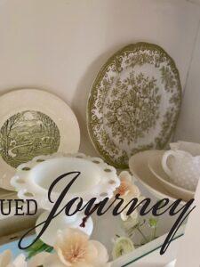 thrifted and vintage dishes styled in a white hutch