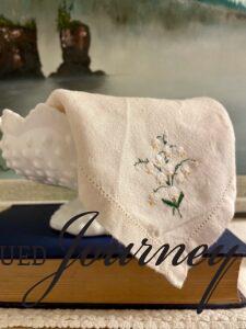 a vintage embroidered hanky displayed in a milk glass bowl