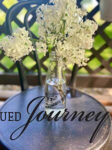 a vintage milk jar filled with white Lilacs