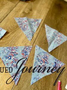 four fabric flags cut out for a DIY bunting banner