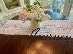 a thrifted eyelet table runner with a vintage vase